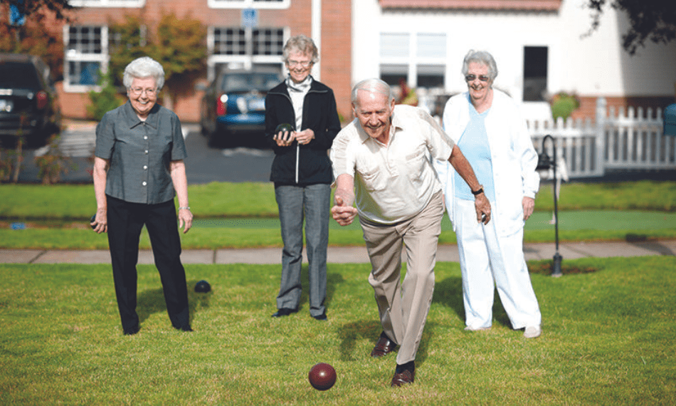 Group of 4 mature people playing pétanque.