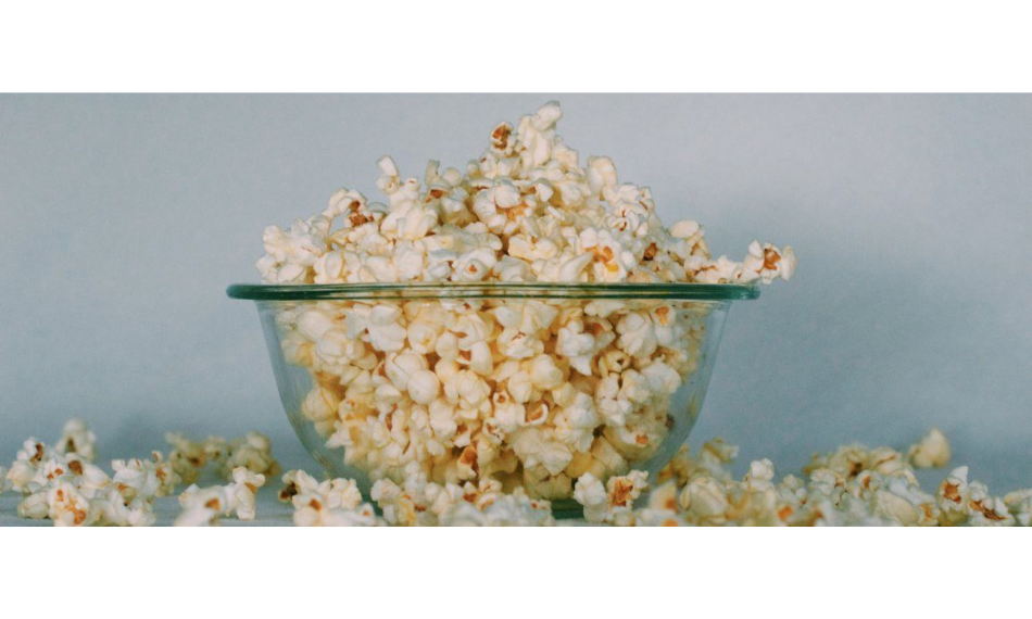 Glass bowl overflowing with popcorn.