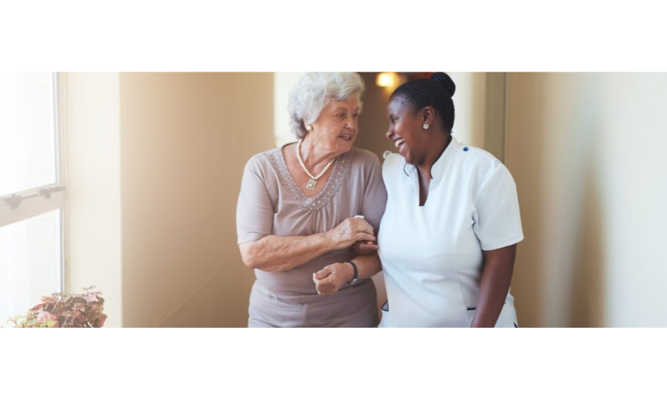 A senior and a personal care worker smiling and talking to each other.