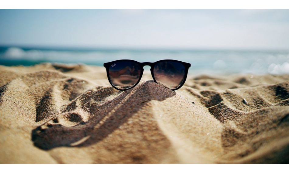 Sunglasses in the sand on the beach.